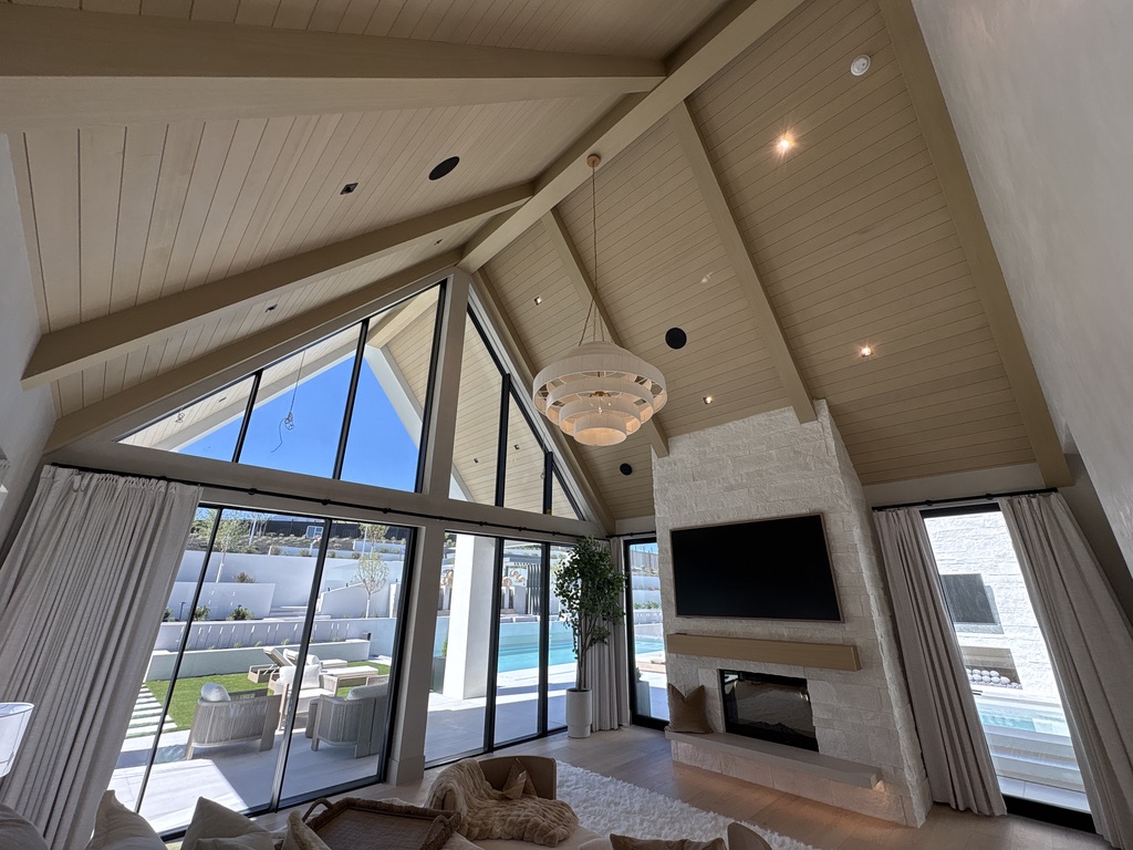 Vaulted A-frame great room with custom beams, floor-to-ceiling windows, and fireplace
