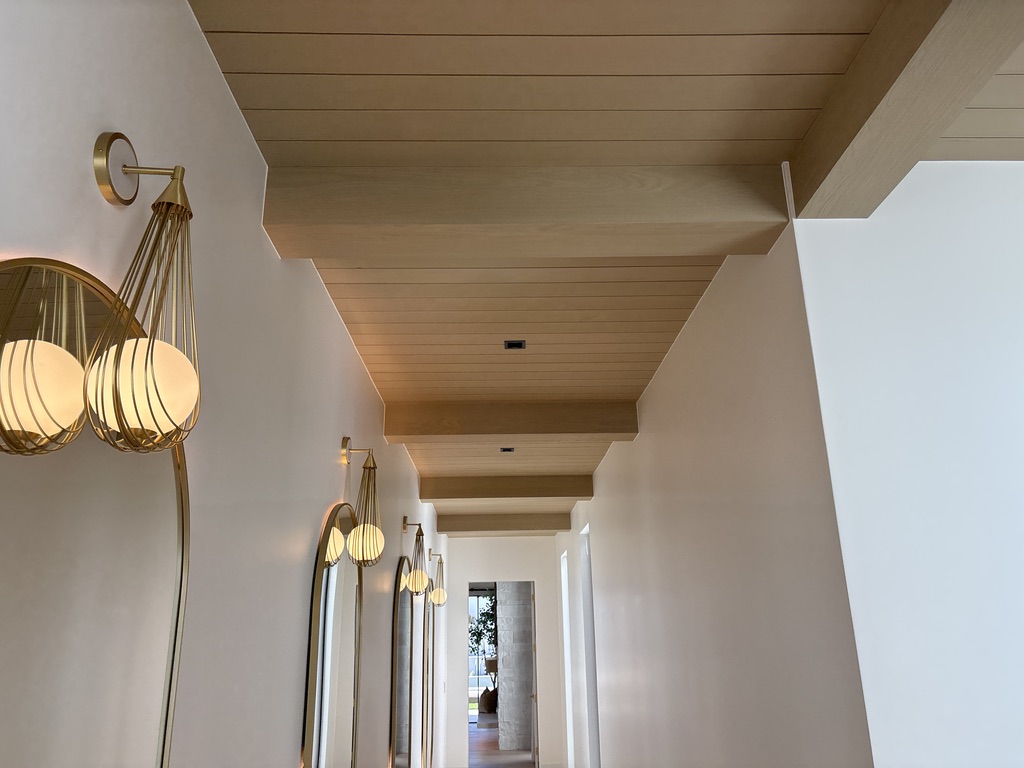 Custom tongue and groove ceiling hallway with brass sconce lighting, luxury custom home